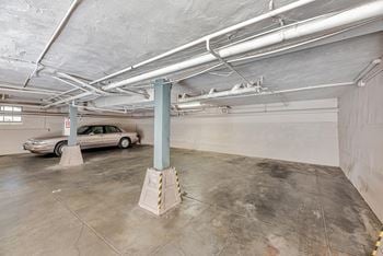 A car is parked in a garage with a concrete floor and white ceiling.