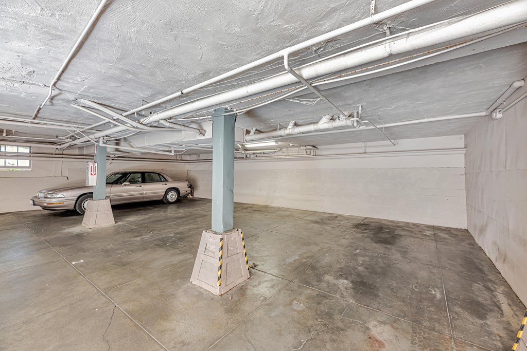 A car is parked in a garage with a concrete floor and white ceiling.