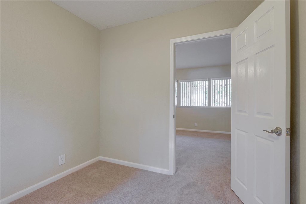 an empty living room with a white door open to a bedroom