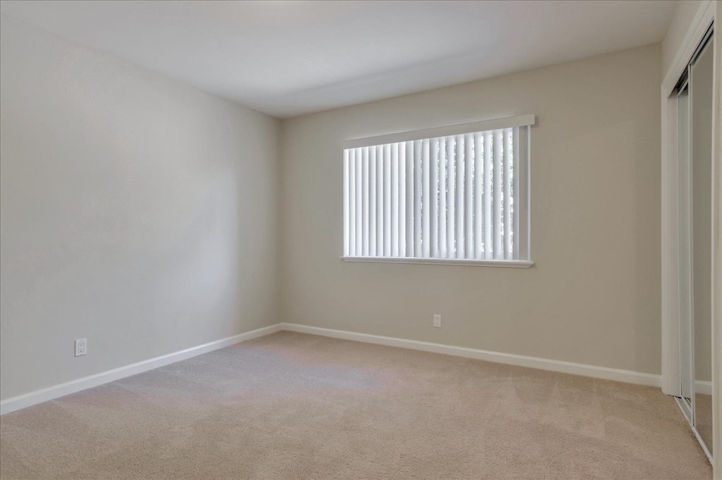 A room with a window covered by white blinds.