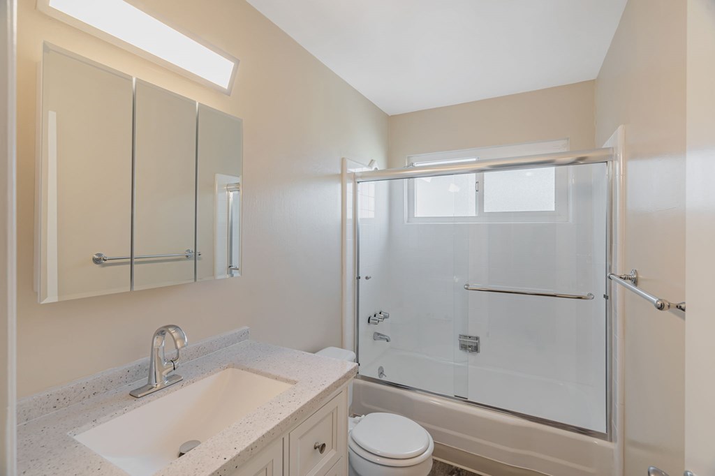 A bathroom with a sink, toilet, and shower.