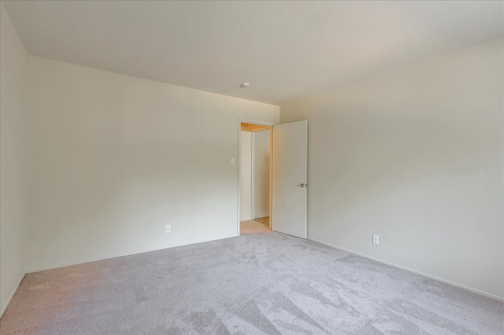 A room with a carpeted floor and a doorway leading to another room.