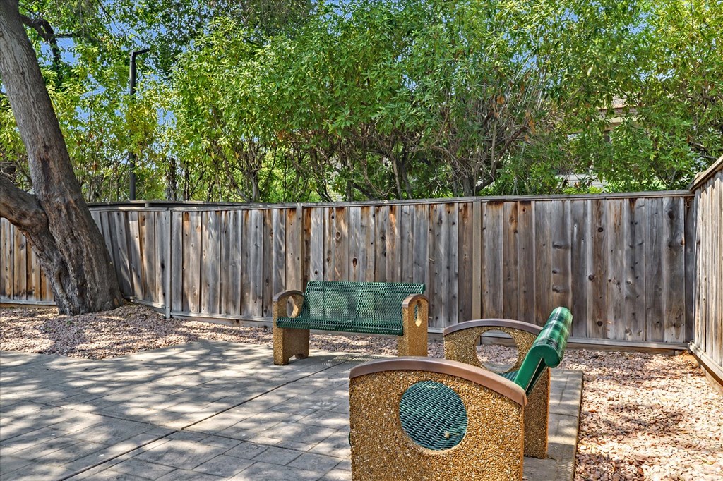 A playground with a wooden fence and two green swings.