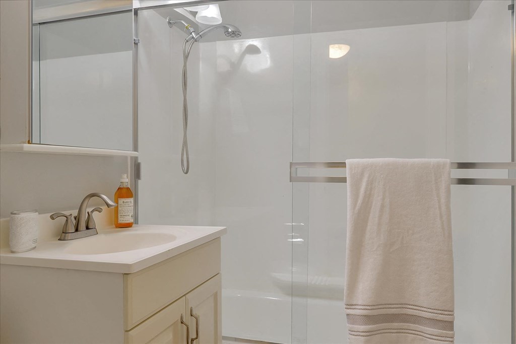 a white bathroom with a shower and a sink and a towel