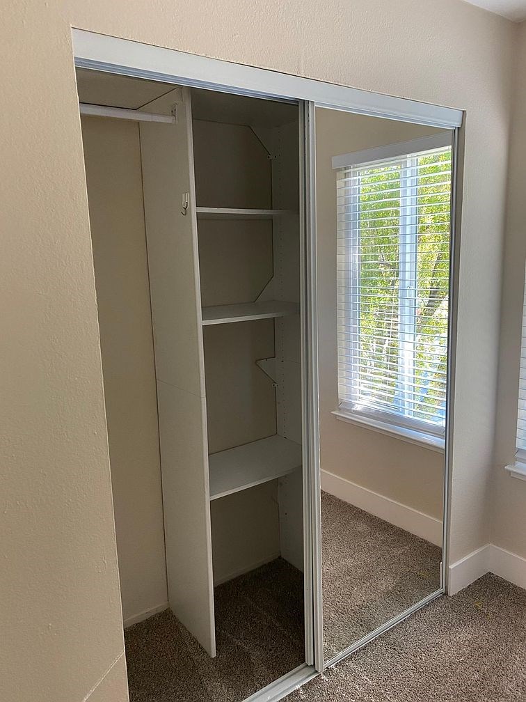 A white closet with a mirrored door is open.
