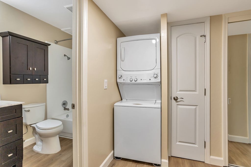 A washer/dryer unit is in a narrow hallway.