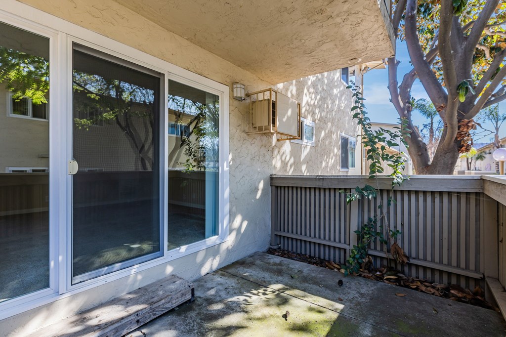 A patio with a sliding glass door and a tree.
