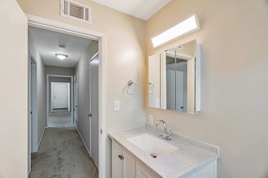 A bathroom with a sink, mirror, and light.