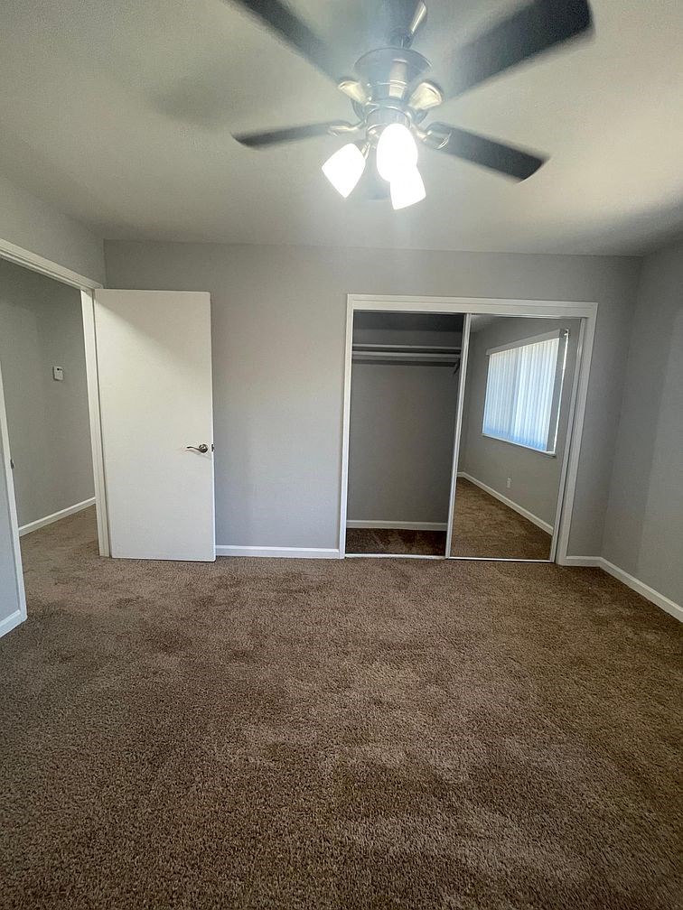 an empty living room with a ceiling fan