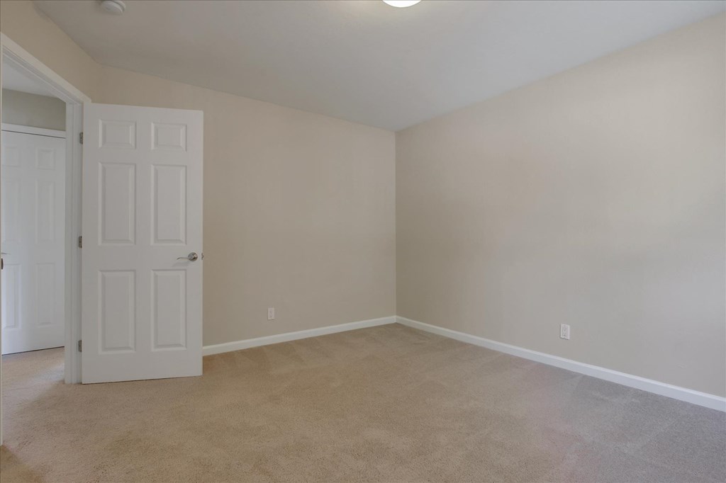 A room with a white door and carpeted floor.
