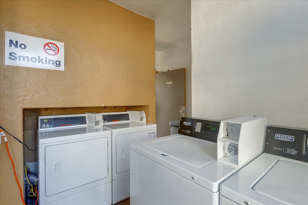 a laundry room with four washing machines and a no smoking sign