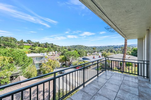 A balcony overlooks a residential area with houses and trees.