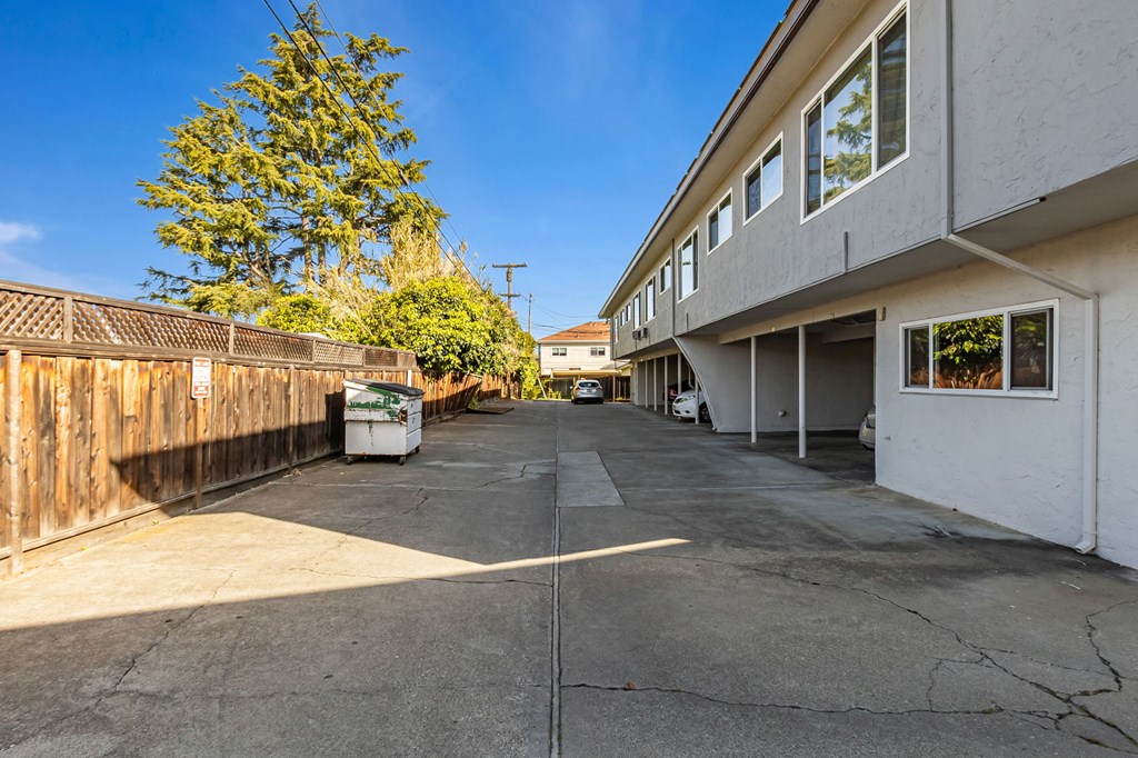 A white trash bin is in the middle of a driveway.