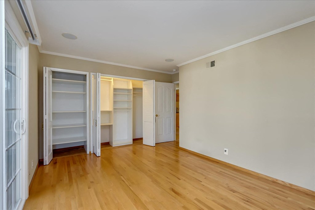 an empty living room with wooden floors and white closets