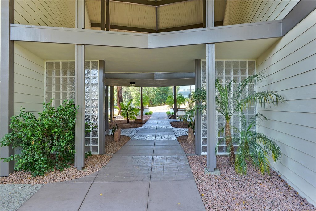 a covered walkway leading to the entrance of a house