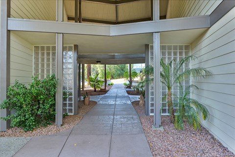 A covered walkway with a concrete floor and white pillars on either side.