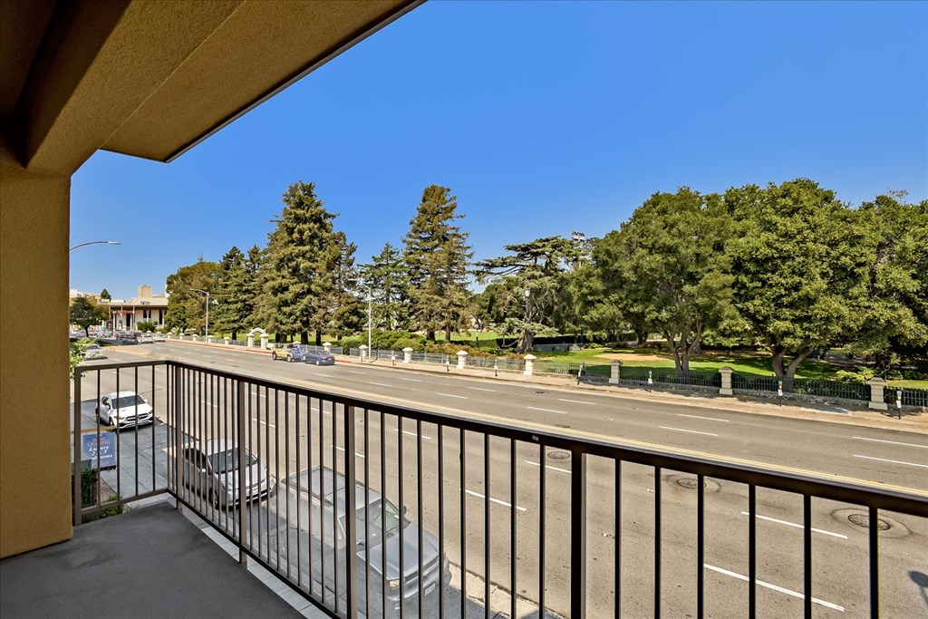 A balcony overlooks a busy street with cars and trees.