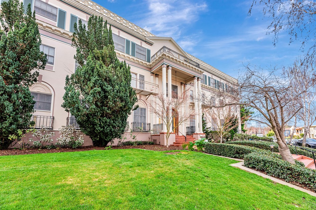 A large, well-maintained lawn in front of a two-story building with a balcony.