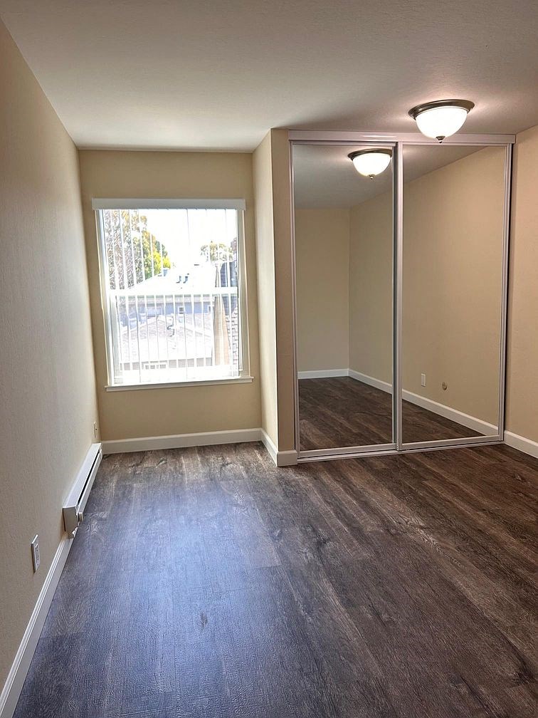 an empty living room with a large window and wooden floors