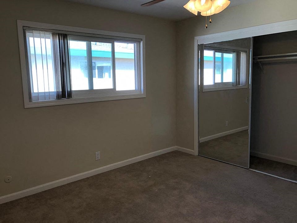 a living room with a mirrored closet and two windows