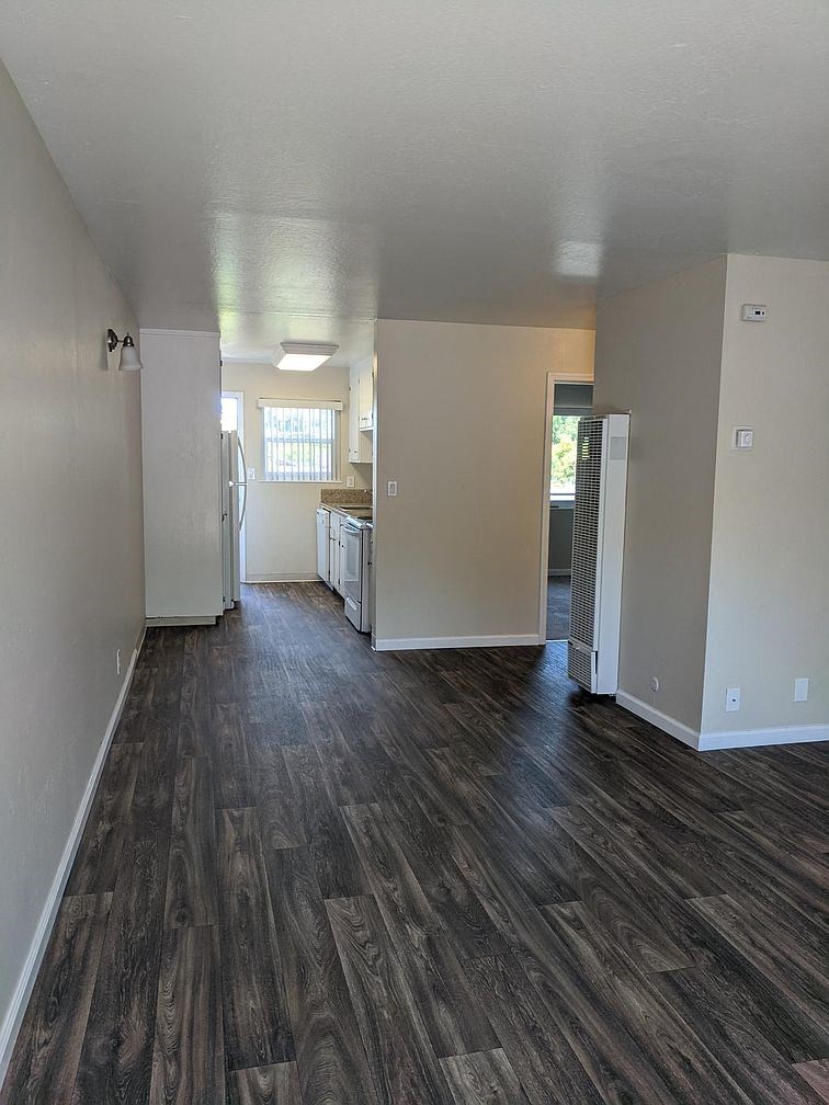 A long hallway with wood flooring and white walls.
