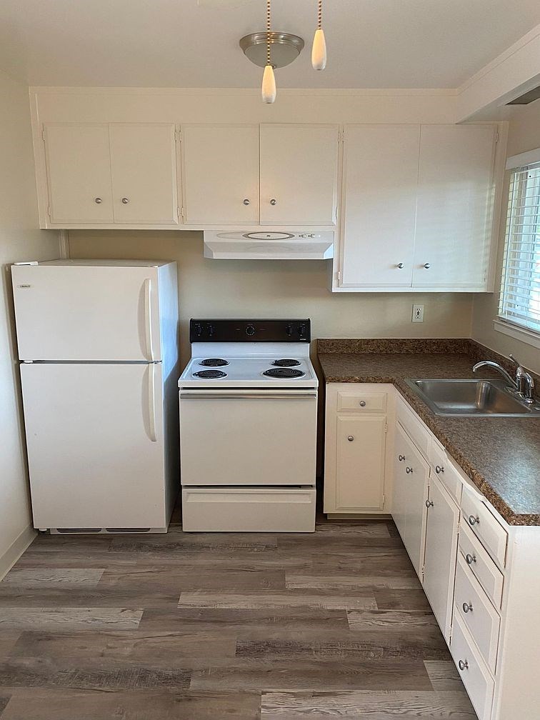 A kitchen with a white refrigerator, stove, and cabinets.
