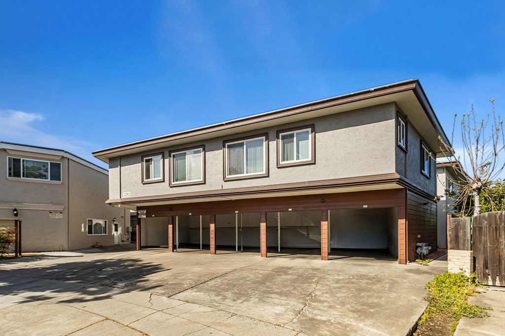 A two-story building with a garage is situated in a sunny area.