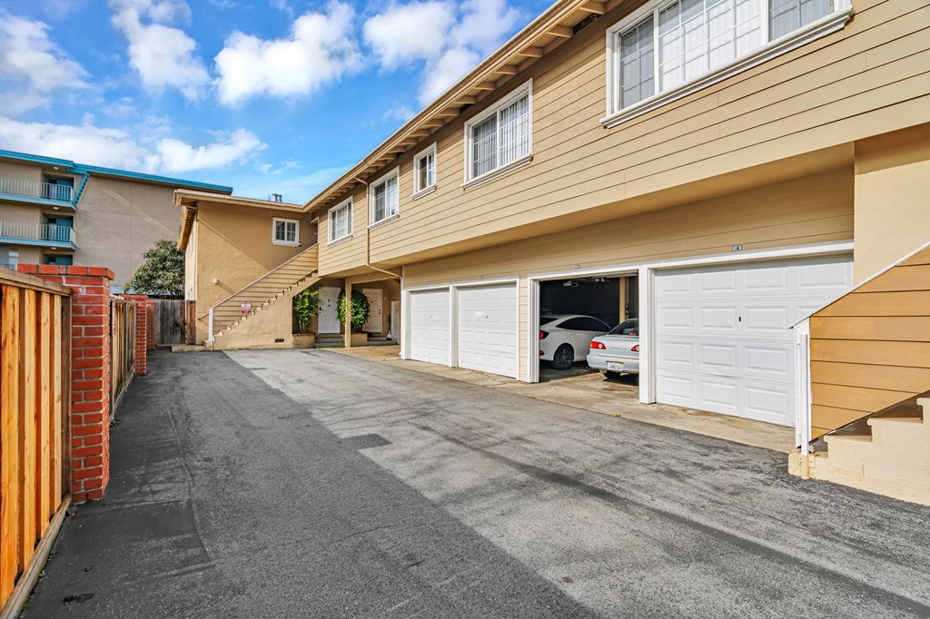 A sunny day at a residential area with a car parked in the driveway.