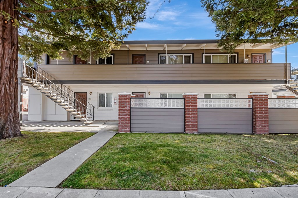 A two-story house with a garage and a tree in front.