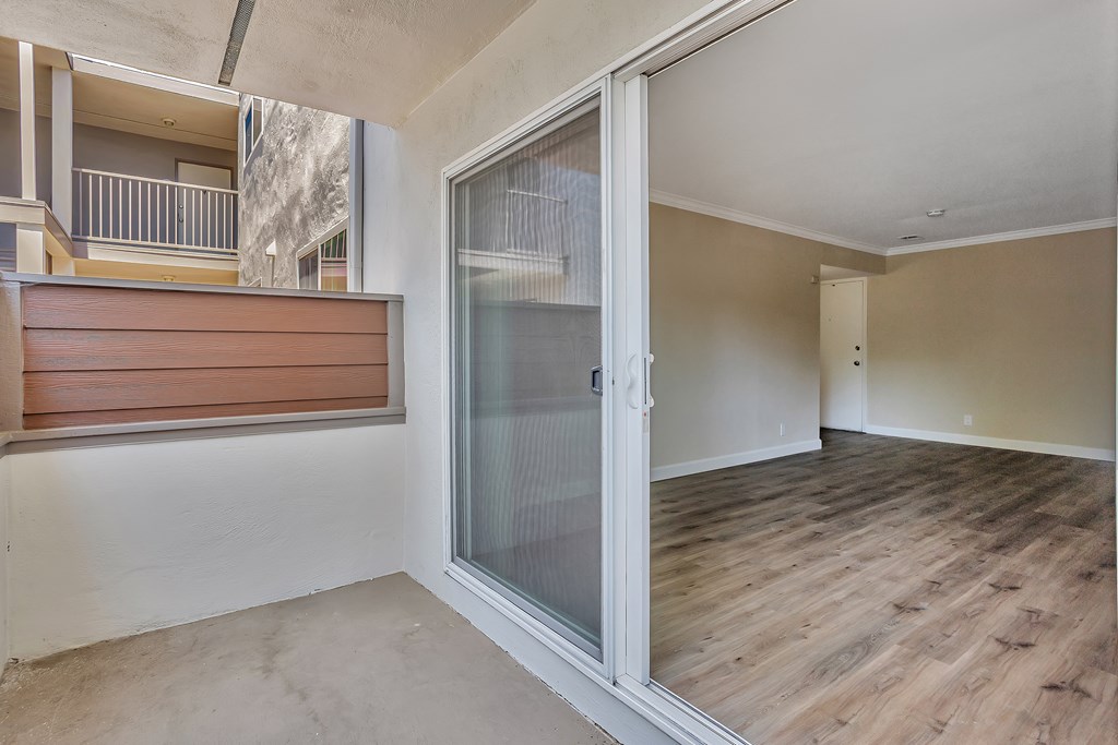 A room with a sliding glass door and wooden flooring.