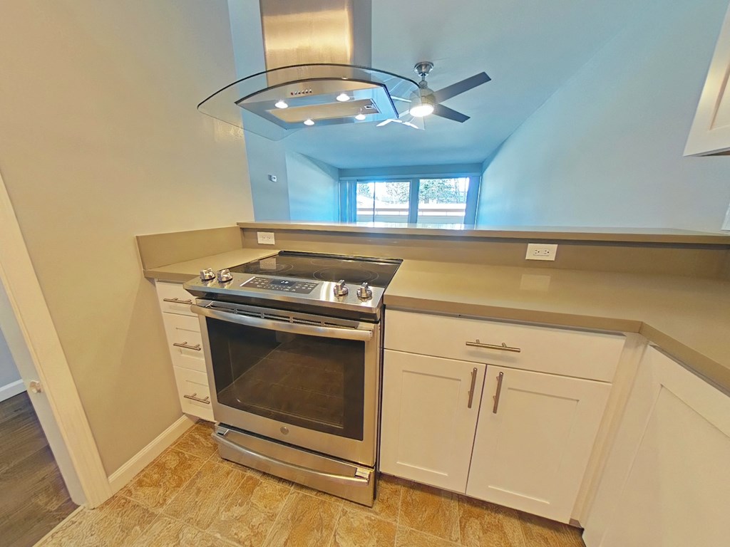 a kitchen with a stove and a ceiling fan