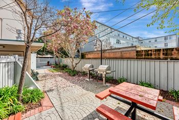 A patio with a picnic table and a tree with pink flowers.