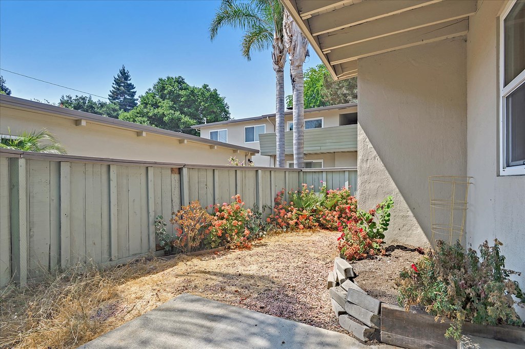 a side yard of a house with a fence and trees