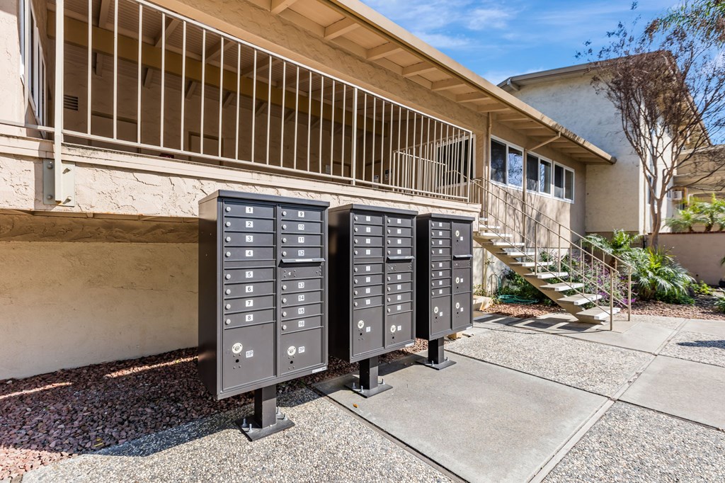 Three large electrical boxes are lined up on a sidewalk outside a building.