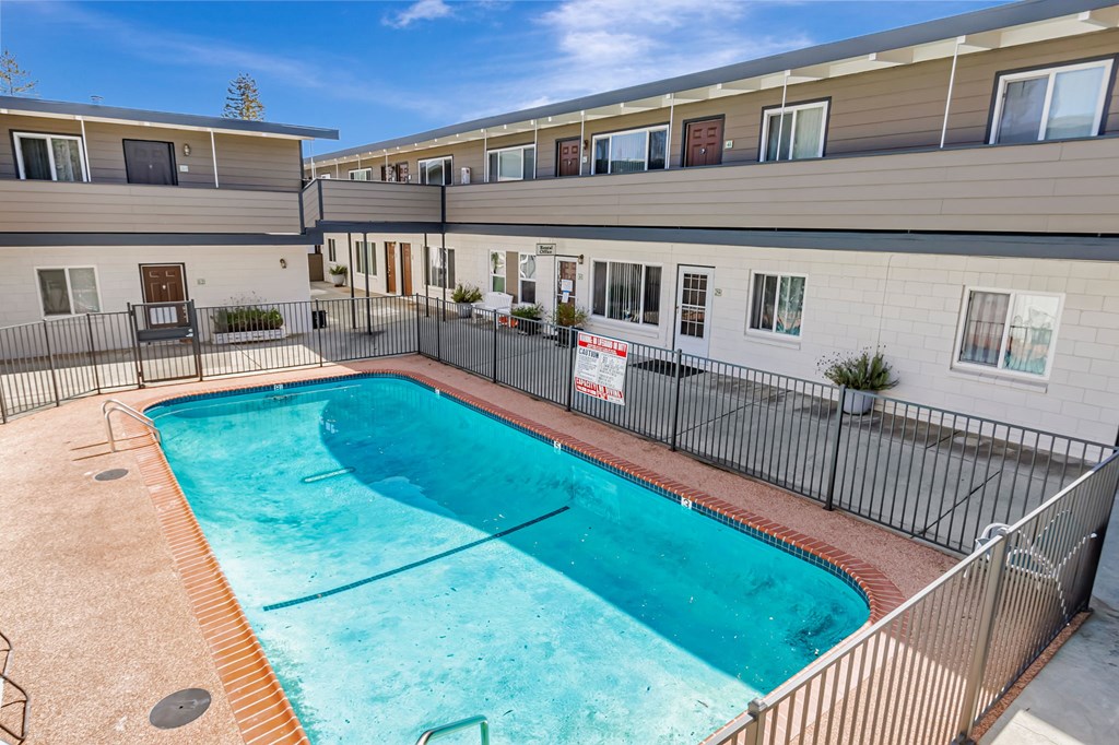 A swimming pool in a residential area surrounded by a fence.