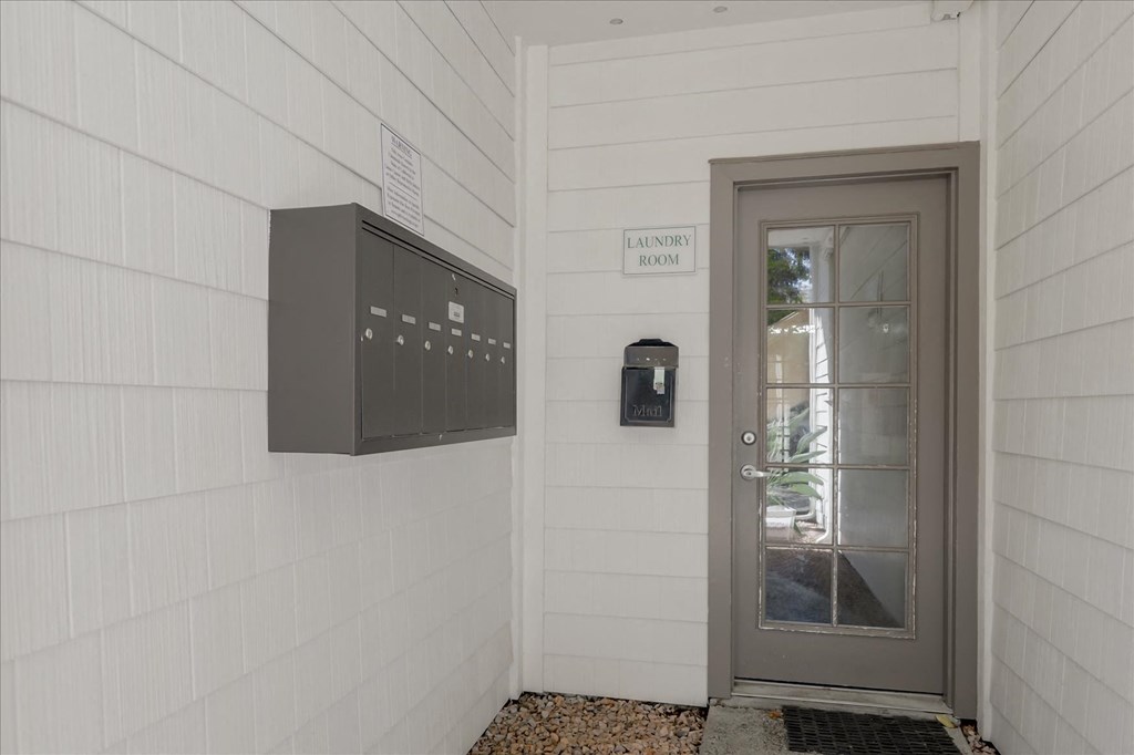 the front door of a white building with a glass door and a mailbox