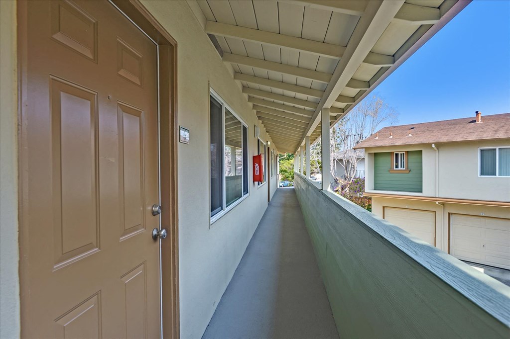 a long porch with a door open to a house