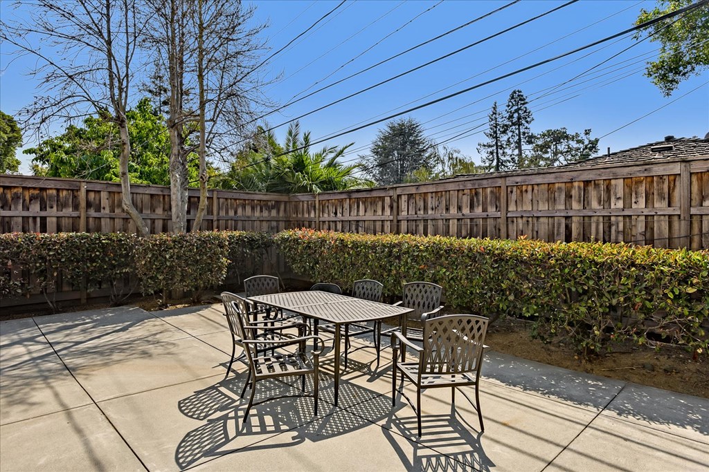 a patio with a table and chairs in front of a fence