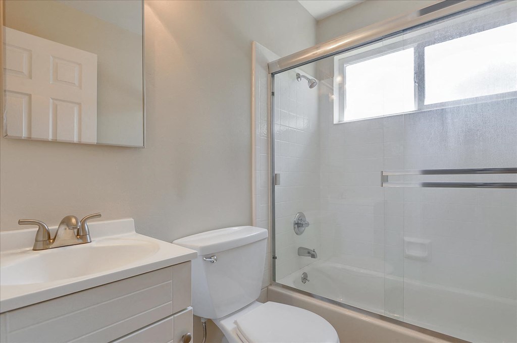 A white bathroom with a toilet, sink, and shower.