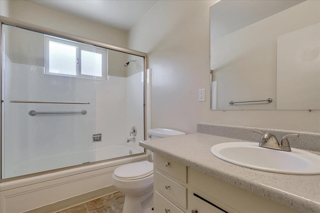 A white toilet sits in a bathroom next to a sink.