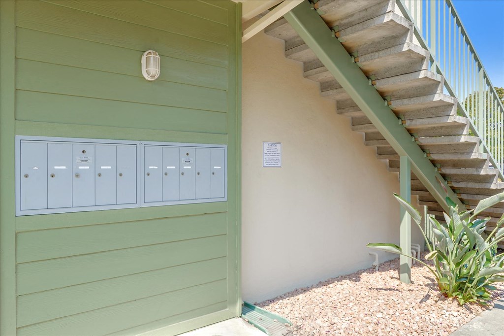 a green building with a staircase and mailboxes next to it