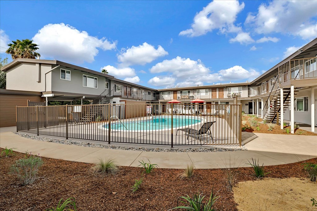 a swimming pool is behind a fence in front of apartment buildings