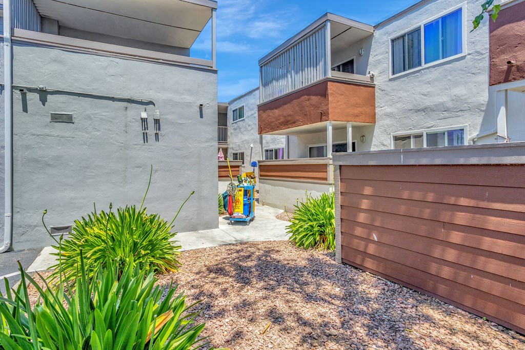A modern building with a brown fence and a small garden in front.