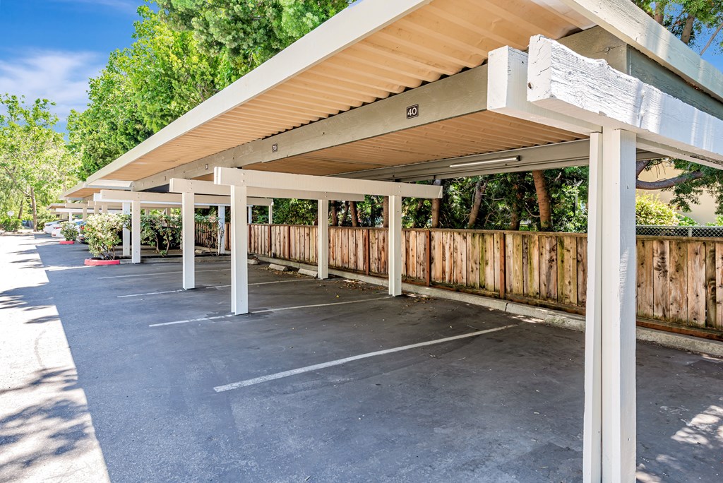 A parking lot with a white canopy and a wooden fence.
