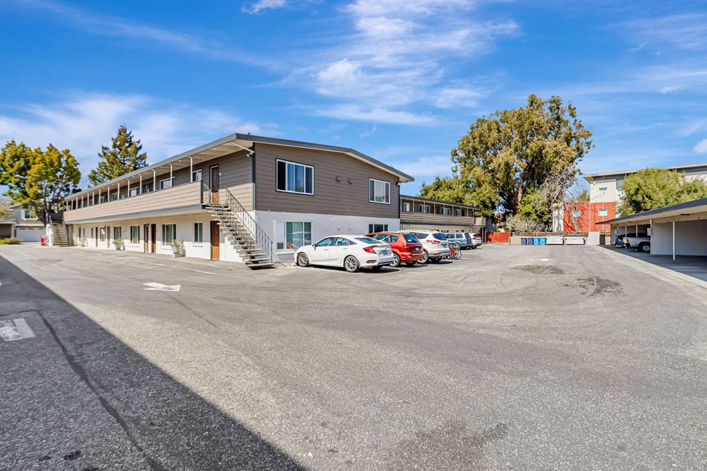 A parking lot with a building and cars parked in front.