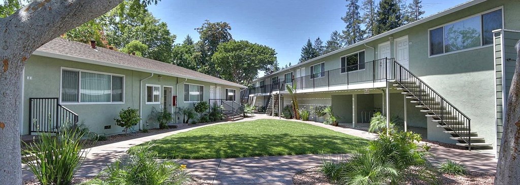 A sunny day at the apartment complex with green grass and trees.