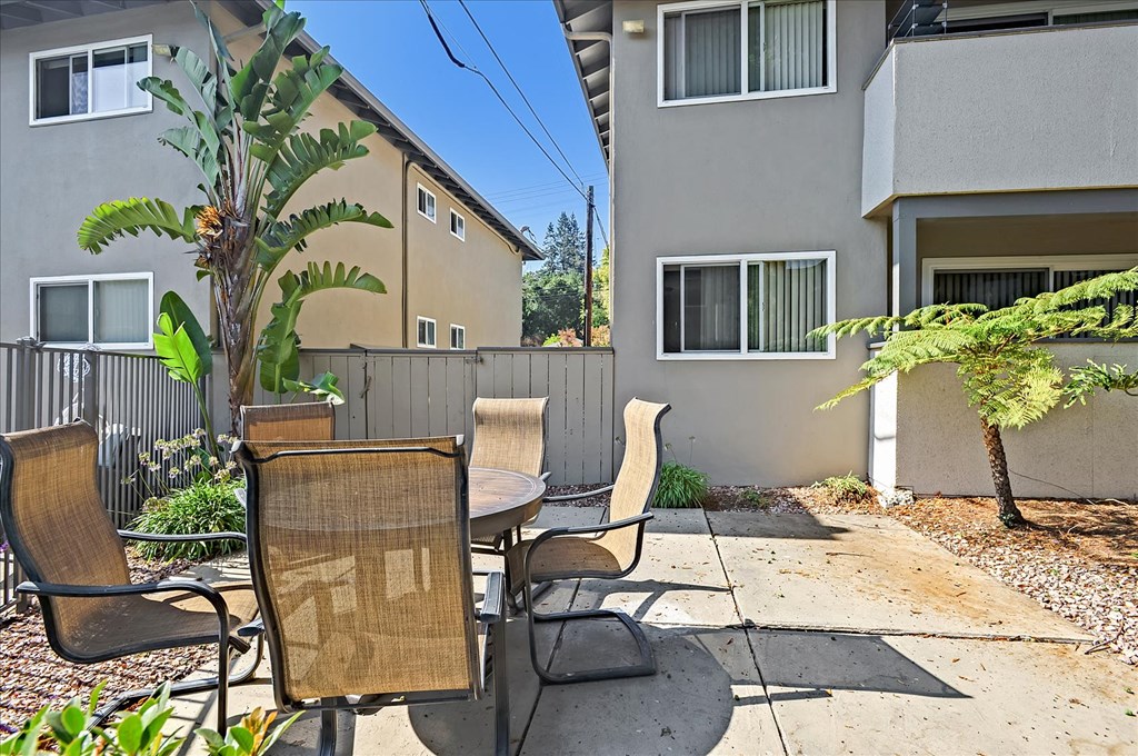 a patio with a table and chairs in front of a building