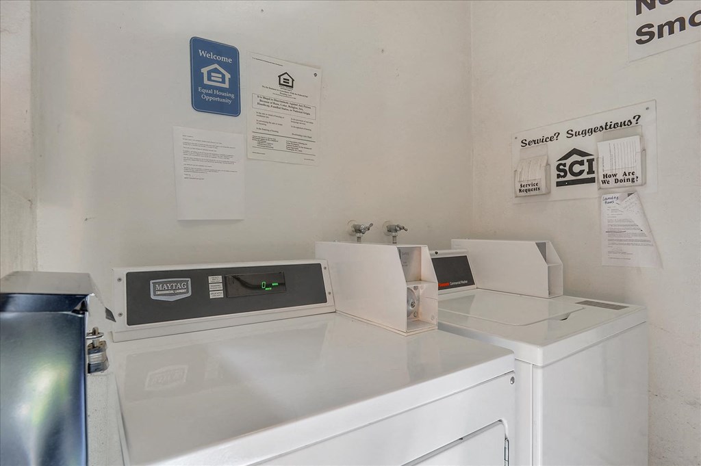 A white washing machine sits next to a dryer in a small room.