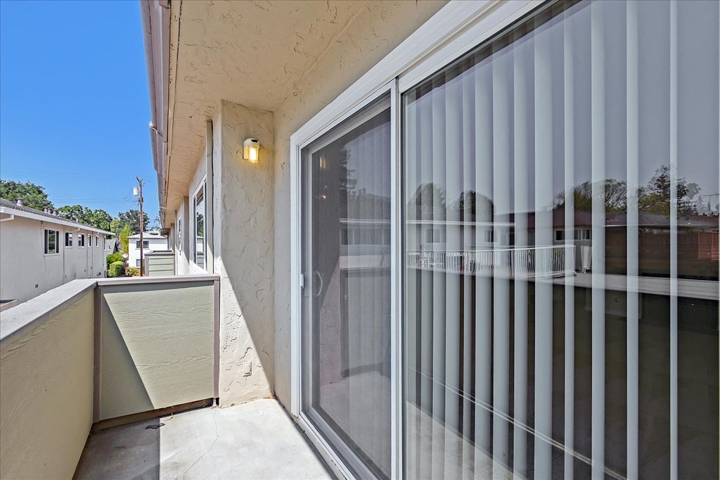 a patio with a glass sliding glass door and a balcony
