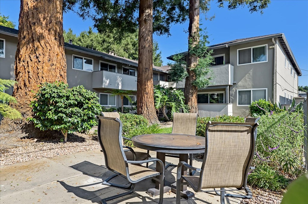 a patio with a table and chairs in front of an apartment building